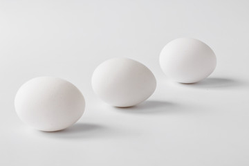 Eggs of natural white color on a light background with shadows. Minimalism. Copy space. Front view. Easter. Selective focus