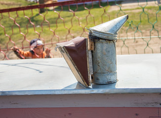 Old  Smoker standing on the hive. A bee smoker  is a device used in beekeeping to calm honey bees. It is designed to generate smoke from the smouldering of various fuels,  hence the name.