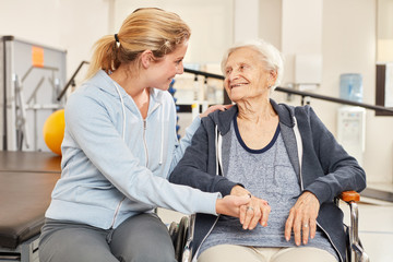 Trainerin betreut eine Senior Frau im Rollstuhl