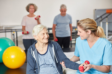 Therapeutin unterstützt Senior Frau beim Hanteltraining