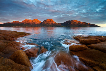 Sunset over The Hazards with Alpine glow and flowing water over rocks, Freycinet National Park,...