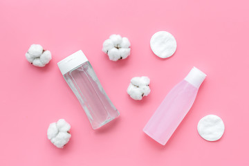 facial tonic, lotion and cotton pads for face care on pink background top view mock up