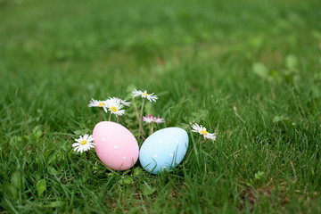 Two easter eggs, ping and blue, in a grass