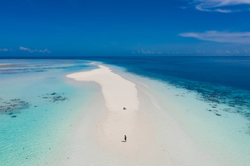 Aerial view of a man walking on the white sand bar in the tropical destination. Hawaii French polynesia Maledives Philippines.
