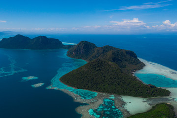 Amazing tropical paradise islands from the air with blue turquoise blue lagoon water and coral reef. Aerial view of Bohey Dulang island panorama. Hawaii, Philippines, French polynesia.
