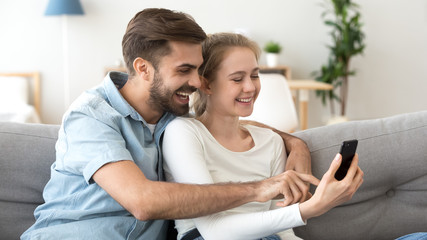 Happy man and woman having fun with smartphone together