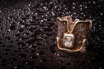 elegant silver crown ring on dark background with water drops