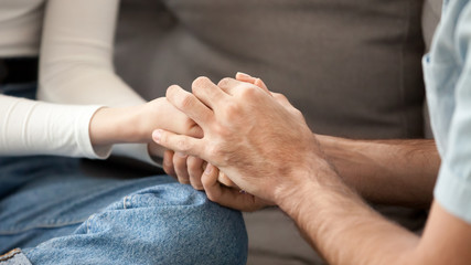 Close up couple in love holding hands, showing support, togetherness