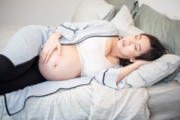 Obraz na płótnie Canvas Beautiful asian pregnant woman is sleeping on bed