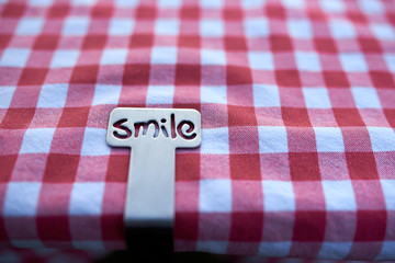 Silbernes Smile Schild auf karierter Tischdecke