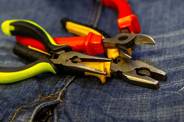 three wire cutters bright plastic green handles red yellow on jeans background close-up tools