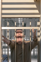 Homme tendant les bras vers la liberté depuis une porte de prison en criant 