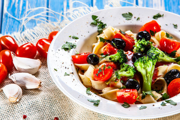Pasta with herbs and vegetables on wooden background