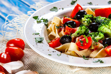 Pasta with herbs and vegetables on wooden background