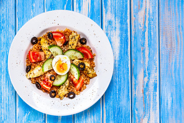 Grilled chicken meat with groats and boiled egg on wooden table