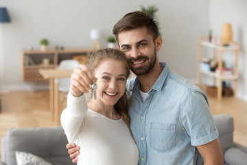 Head shot portrait of happy couple in love holding keys, hugging