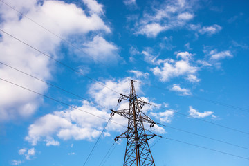Power line transmission lines against a blue sky with clouds.