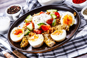 Grilled chicken meat with groats and boiled egg on wooden table