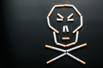 Skull from cigarettes on a black background. The concept of smoking kills. Toward the concept of smoking as a deadly habit, nicotine poisons, cancer from smoking, illness, quit smoking.