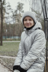 Girl 30 years old in warm clothes on the street in the park.