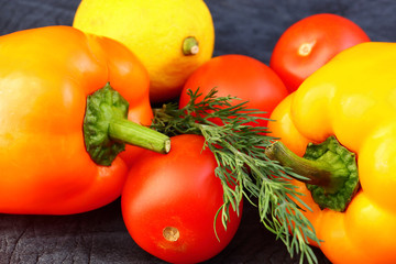 Bright vegetables and fruits (yellow and orange peppers, red tomatoes, yellow lemon, green dill).