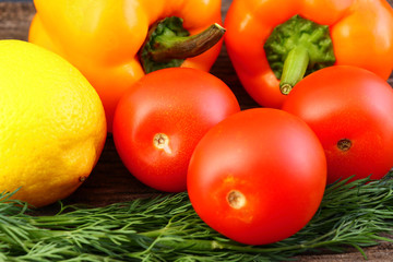 Bright vegetables and fruits (yellow and orange peppers, red tomatoes, yellow lemon, green dill).