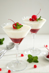 Glasses of delicious panna cotta on white table