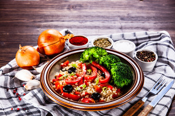 Groats with vegetables on wooden table