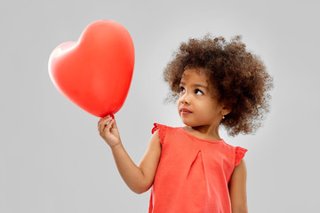 childhood and people concept - happy little african american girl with red heart shaped balloon...
