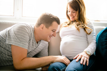 Fototapeta premium A happy man with pregnant woman sitting on couch