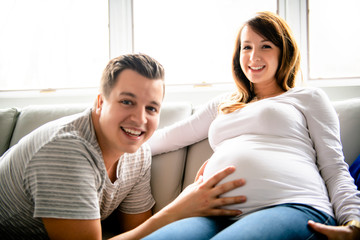 A happy man with pregnant woman sitting on couch
