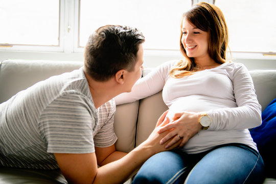 A happy man with pregnant woman sitting on couch