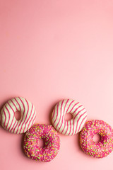 Creative layout made of pink glazed donuts. Flat lay. Food concept. Macro concept. Various decorated doughnuts on soft pink background. Sweet and colourful doughnuts 