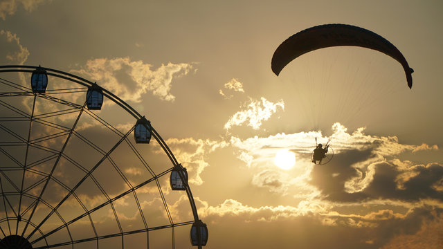 Parachuter flying on the sky, around the ferris wheel.