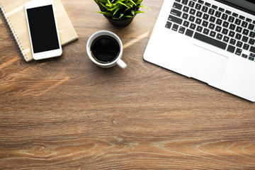 Wood desk table with smartphone with blank mock up screen, laptop computer and up of coffee with...