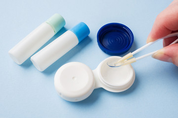 Tweezers with contact lens and plastic container for lens storage. Close up. Selective focus.