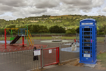 A traditional telephone box converted into a Little Free Library stands conveniently next to the playground so children can pick up a book as they go home