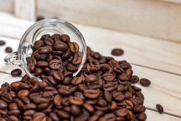 Cup and grain of coffee over white wooden background