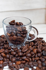 Cup and grain of coffee over white wooden background