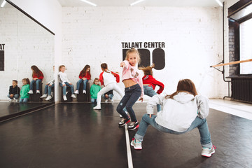 The kids at dance school. Ballet, hiphop, street, funky and modern dancers over studio background. Children showing aerobic element. Teens in hip hop style. Sport, fitness and lifestyle concept.