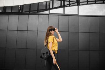 Beautiful brown-haired model girl in the yellow sleeveless shirt and in the fashionable sunglasses...