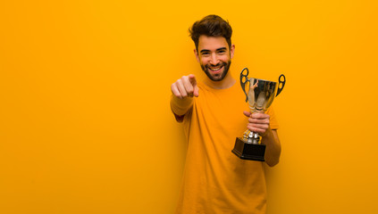 Young man holding a trophy cheerful and smiling