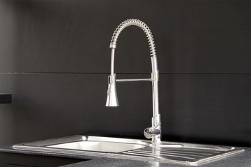 Modern kitchen faucet on black background.