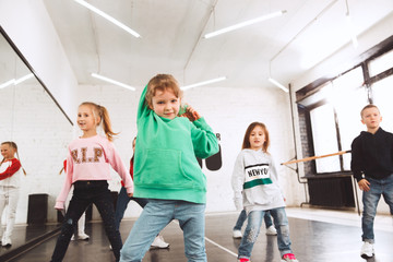 The kids at dance school. Ballet, hiphop, street, funky and modern dancers over studio background. Children showing aerobic element. Teens in hip hop style. Sport, fitness and lifestyle concept.