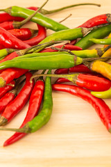 green red pod hot peppers lots of vegetables on a wooden background close-up