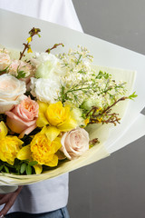 spring fresh bouquet of flowers and greenery, approaching spring in the hands, skillful work of a florist