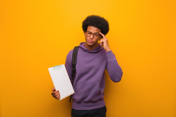 Young african american student man holding a clipboard thinking about an idea