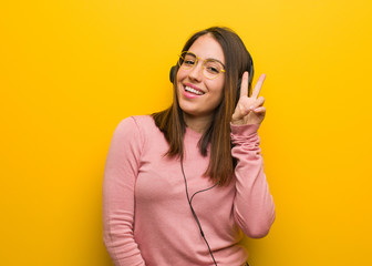 Fototapeta premium Young cute woman listening to music fun and happy doing a gesture of victory
