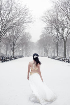 Woman dressed in a white gown standing in the snow, Central Park, Manhattan, New York, United States