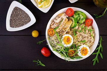 Fresh salad. Breakfast bowl with oatmeal, chicken fillet, tomato, lettuce, microgreens and boiled egg. Healthy food. Vegetarian buddha bowl. Top view